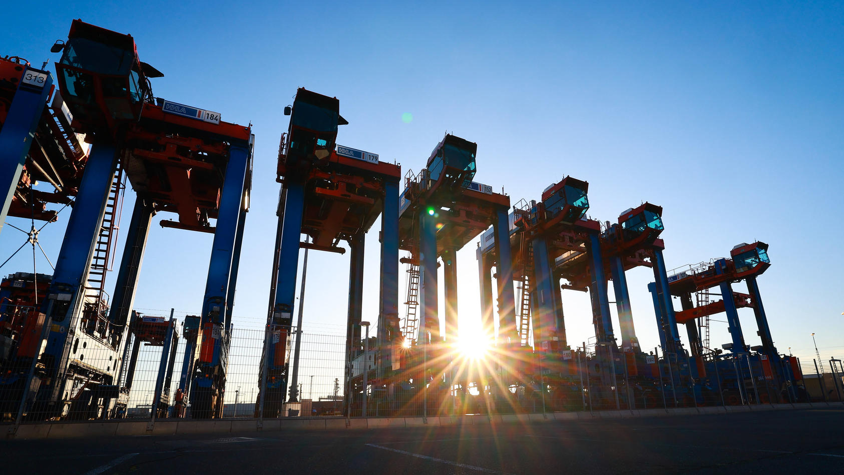 ARCHIV - 14.07.2022, Hamburg: Van Carrier (VC), Spezialfahrzeuge für den Containerumschlag, stehen auf dem Gelände des Container Terminal Burchardkai (CTA) der HHLA (Hamburger Hafen und Logistik AG). Die deutsche Wirtschaft wird nach Einschätzung vie