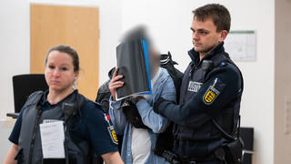 26.01.2023, Baden-Württemberg, Konstanz: Ein Mann (M), der wegen Vergewaltigung und Freiheitsberaubung an seiner Schwester angeklagt ist, verdeckt sein Gesicht, während er von Justiz Beamten in den Gerichtssaal geführt wird. Der Angeklagten soll seine, zur Tatzeit 18-jährige, Schwester in seinem WG-Zimmer in Konstanz eingesperrt, verletzt und mehrmals vergewaltigt haben. Foto: Silas Stein/dpa +++ dpa-Bildfunk +++