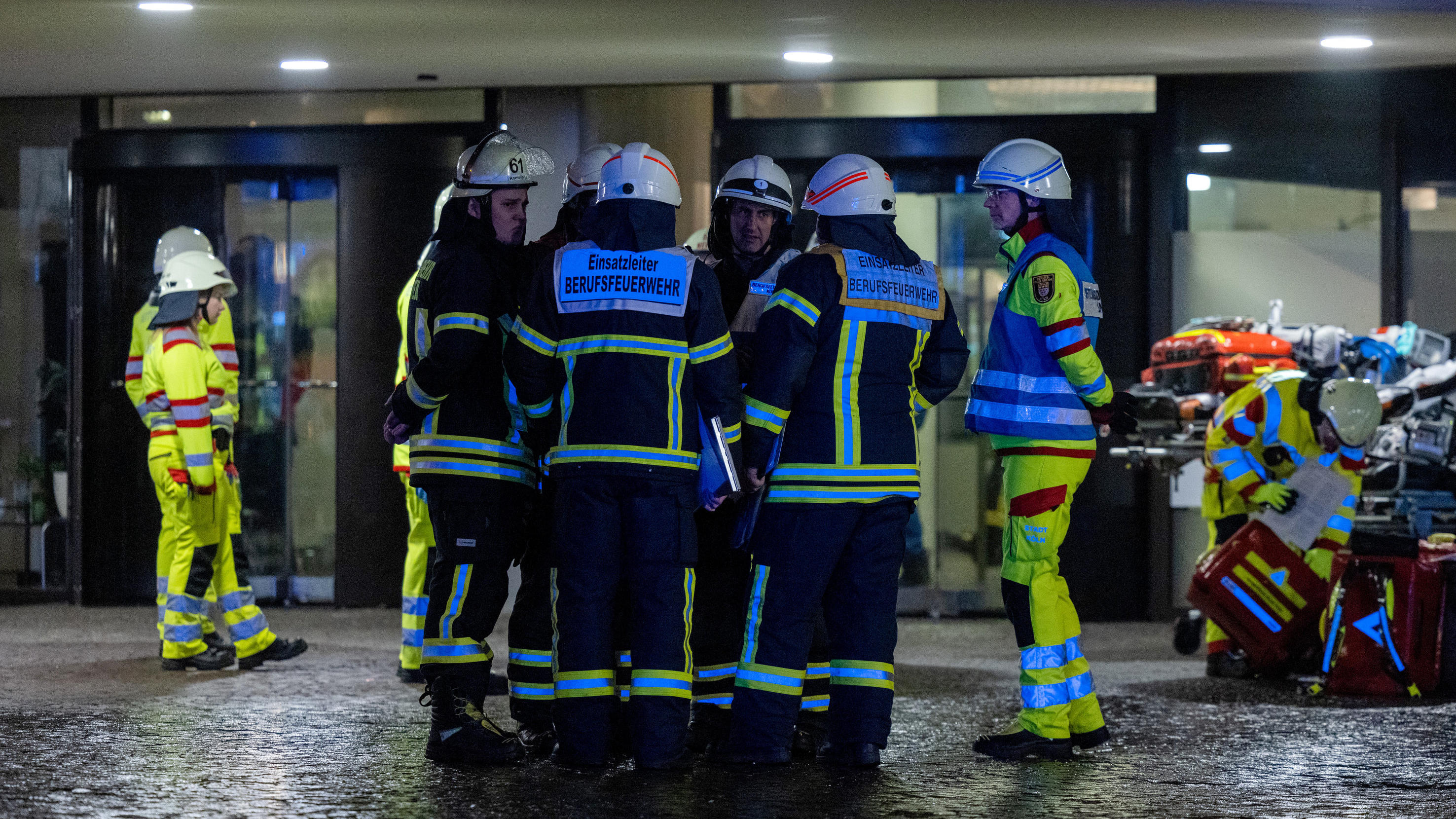PRODUKTION - 26.01.2023, Nordrhein-Westfalen, Köln: Einsatzkräfte der Feuerwehr stehen vor dem Uni-Center. Im Uni-Center Köln, das als eines der größten Wohnhäuser in Europa gilt, ist am Donnerstagabend ein Feuer ausgebrochen. Mehrere Anrufer hätten 