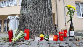 26.01.2023, Baden-Württemberg, Bad Mergentheim: Blumen und Kerzen liegen in der Nähe der Stelle, an der einer ältere Radfahrerin gestürzt war, auf dem Boden. Ein Jugendlicher soll die 78-Jährige  unvermittelt vom Fahrrad gestoßen haben. Dabei zog sich die Frau der Polizei zufolge schwere Kopfverletzungen zu an denen sie später starb. Foto: Heiko Becker/dpa +++ dpa-Bildfunk +++