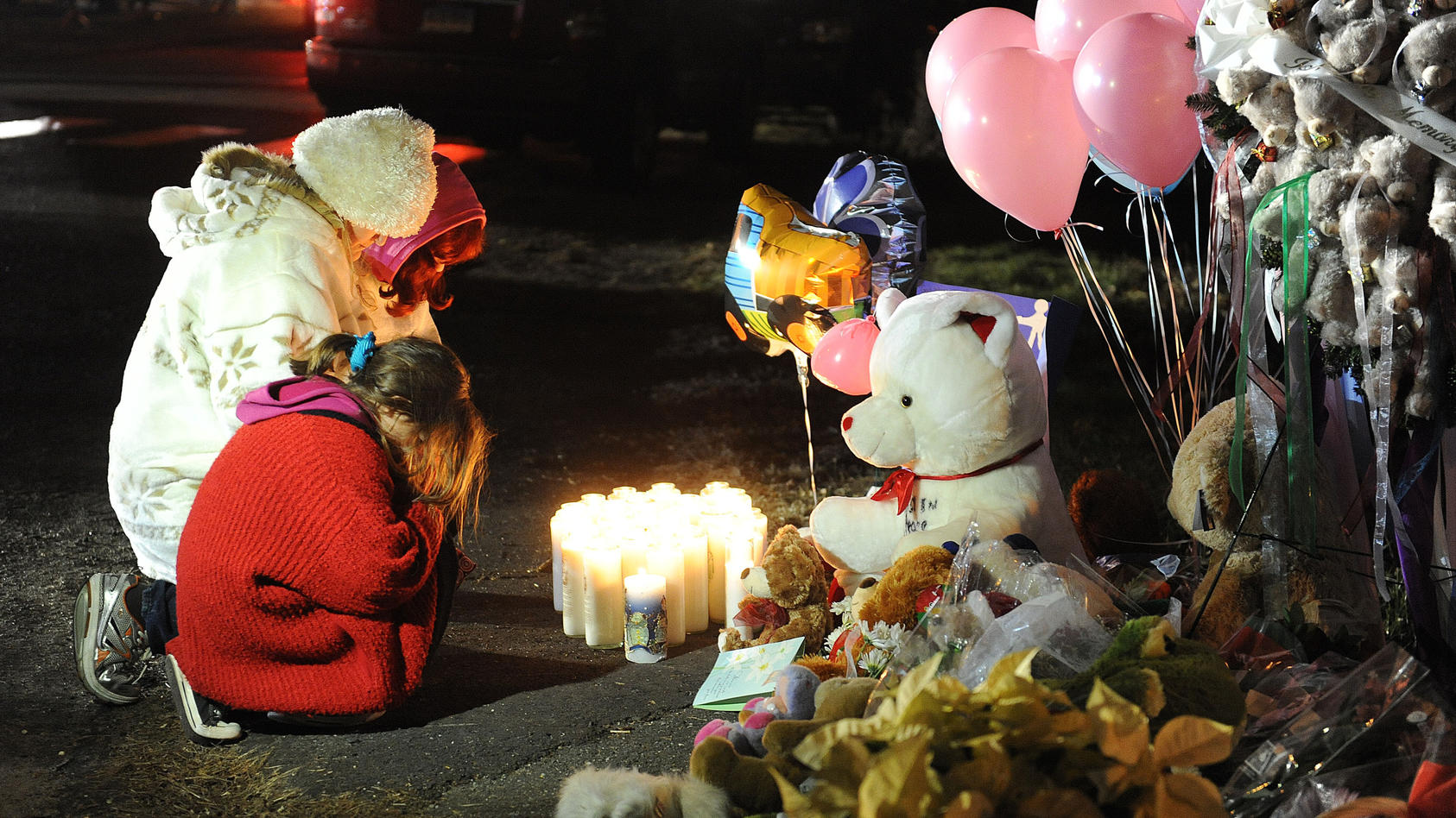 People lights candles at the entrance to the street leading to the Sandy Hook Elementary School on December 15, 2012 in Newtown, Connecticut. Twenty six people were shot dead, including twenty children, after a gunman identified as Adam Lanza opened 