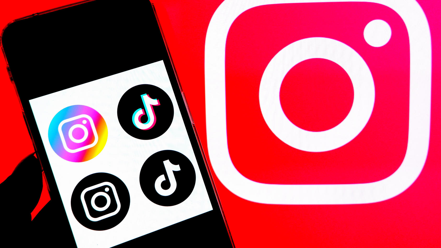 In this photo illustration, a Tiktok and Instagram logos seen displayed on a smartphone with an Instagram logo in the background.