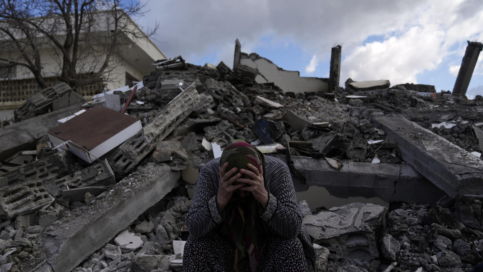 07.02.2023, Türkei, Osmaniye: Eine Frau sitzt auf Trümmern, nach dem verheerenden Erdbeben. Mehr als 13 Millionen Menschen in der Türkei sind nach Einschätzung der Regierung von der Erdbebenkatastrophe betroffen. Foto: Khalil Hamra/AP/dpa +++ dpa-Bil