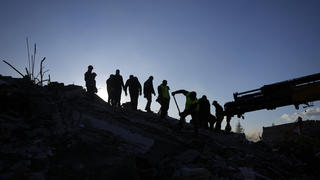 08.02.2023, Türkei, Antakya: Rettungsteams suchen nach Menschen in den Trümmern zerstörter Gebäude. In den Erdbeben-Gebieten in Syrien und der Türkei werden bei der Suche nach Verschütteten immer mehr Leichen aus den Resten eingestürzter Gebäude geborgen. Mehrfach korrigierten die türkischen Behörden am Mittwoch die Zahl bestätigter Opfer nach oben. Foto: Khalil Hamra/AP/dpa +++ dpa-Bildfunk +++