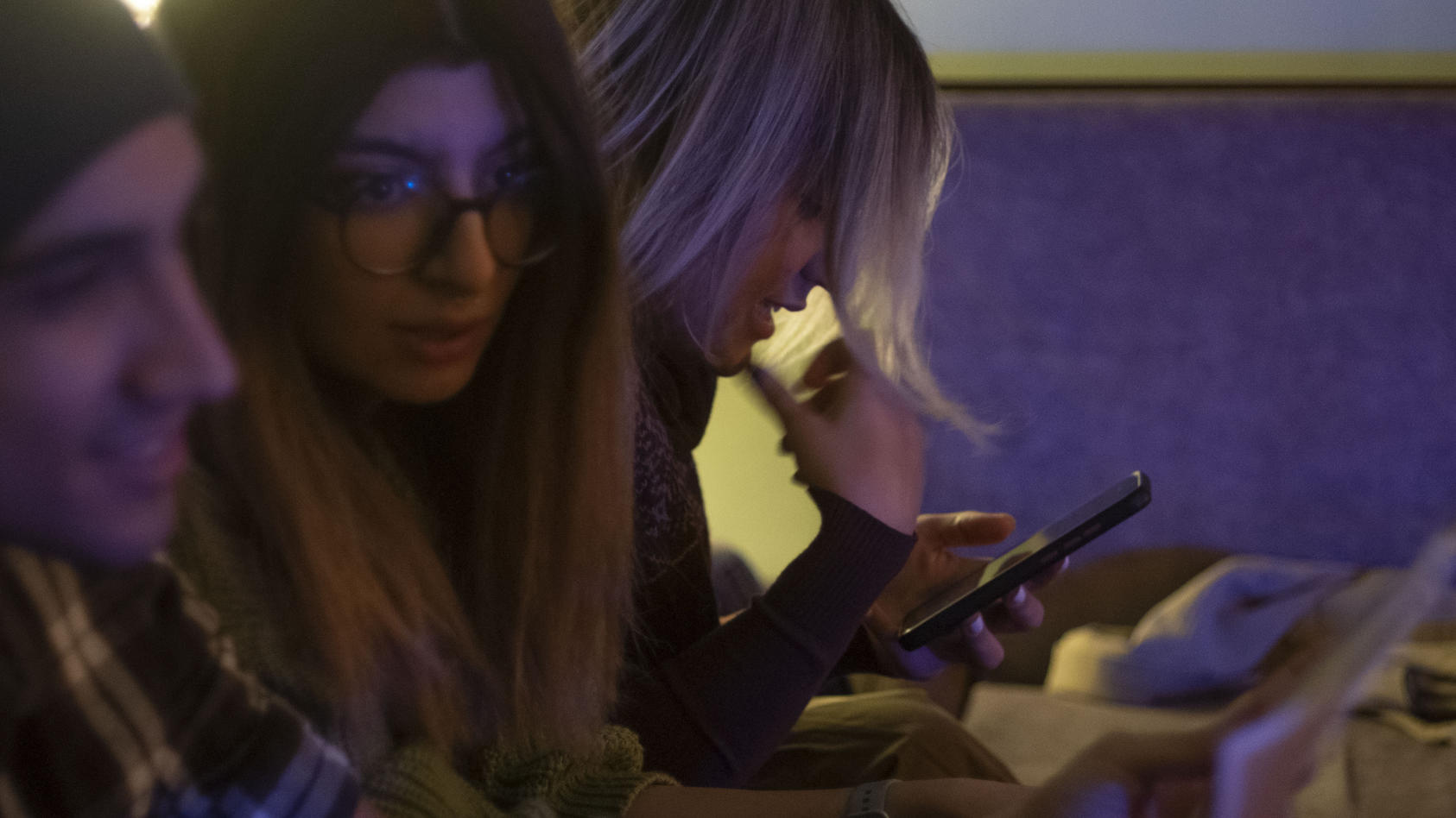 An Iranian young woman uses her smartphone to check her social media pages while waiting for an underground music performance at a cafe in downtown Tehran at night, January 18, 2023. Tehran seems more calm after months of unrest, with youths gatherin
