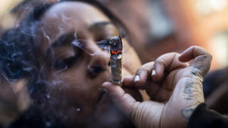 A person smokes cannabis outside the Smacked "pop up" cannabis dispensary location, Tuesday, Jan. 24, 2023, in New York. The store is the first Conditional Adult-Use Retail Dispensary (CAURD) opening since the legalization of cannabis that is run by businesspeople who had been criminalized by cannabis prohibition. (AP Photo/John Minchillo)