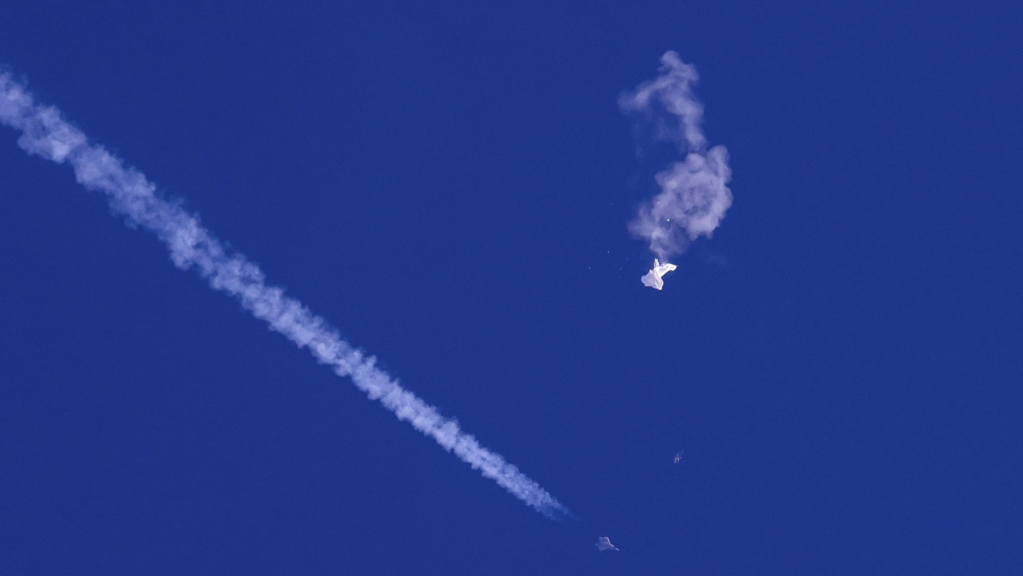 dpatopbilder - 04.02.2023, USA, -: Auf diesem von Chad Fish zur Verfügung gestellten Bild schweben die Überreste eines großen Ballons über dem Atlantischen Ozean vor der Küste South Carolinas. Darunter sind ein Kampfjet und seine Kondensstreifen zu s