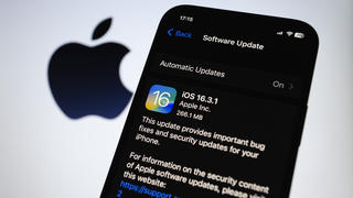 iPhone mit Update auf Bildschirm und Apple Logo im Hintergrund