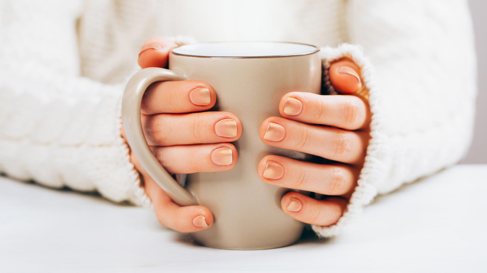 Frau mit Cappuccino Nails hält Kaffee.