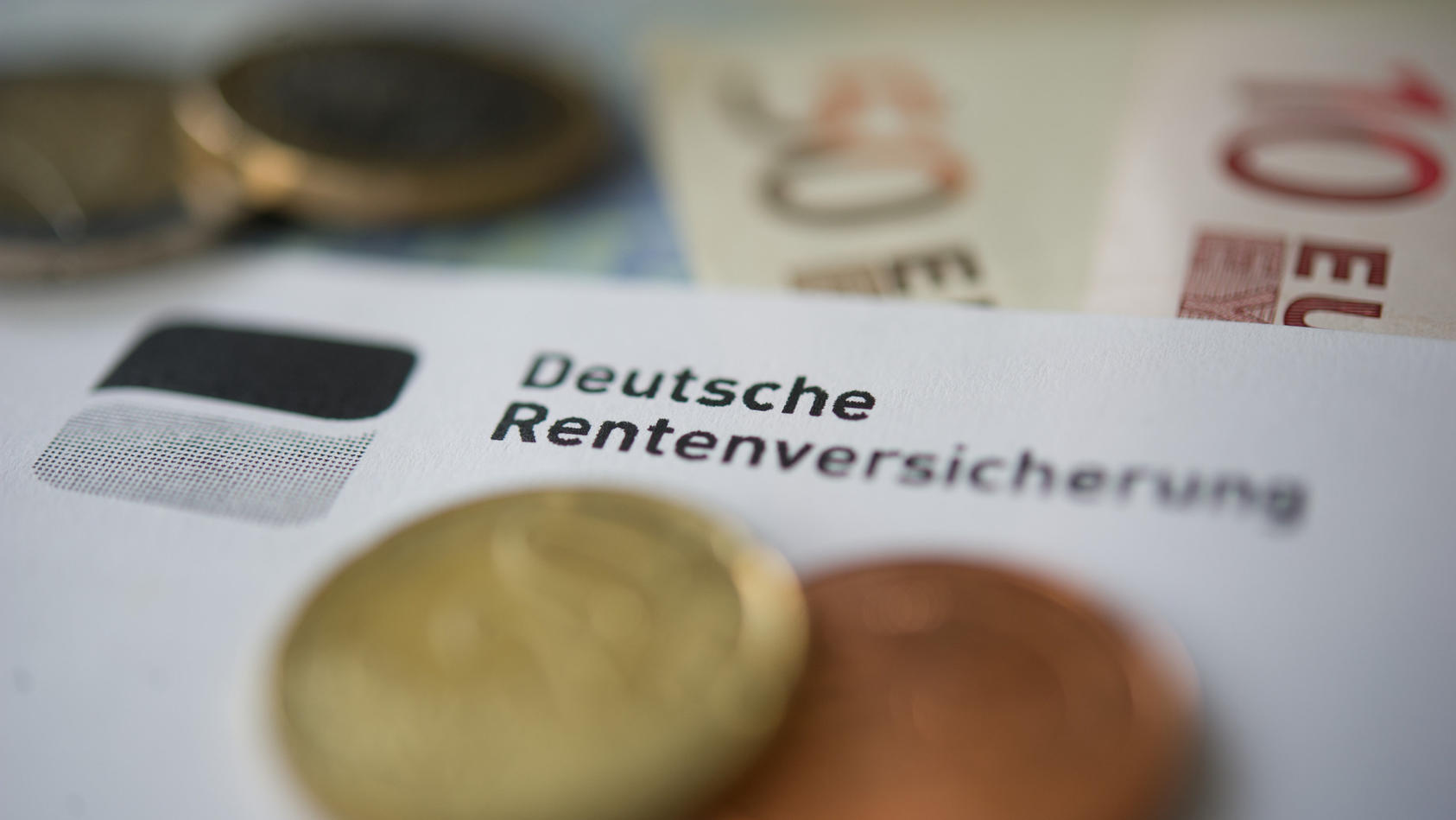 ARCHIV - 21.06.2012, Baden-Württemberg, Stuttgart: ILLUSTRATION - Münzen und Geldscheine liegen neben einem Schreiben mit der Aufschrift «Deutsche Rentenversicherung». (zu dpa «Erwerbstätige ziehen höhere Rentenbeiträge einer späteren Rente vor») Fot