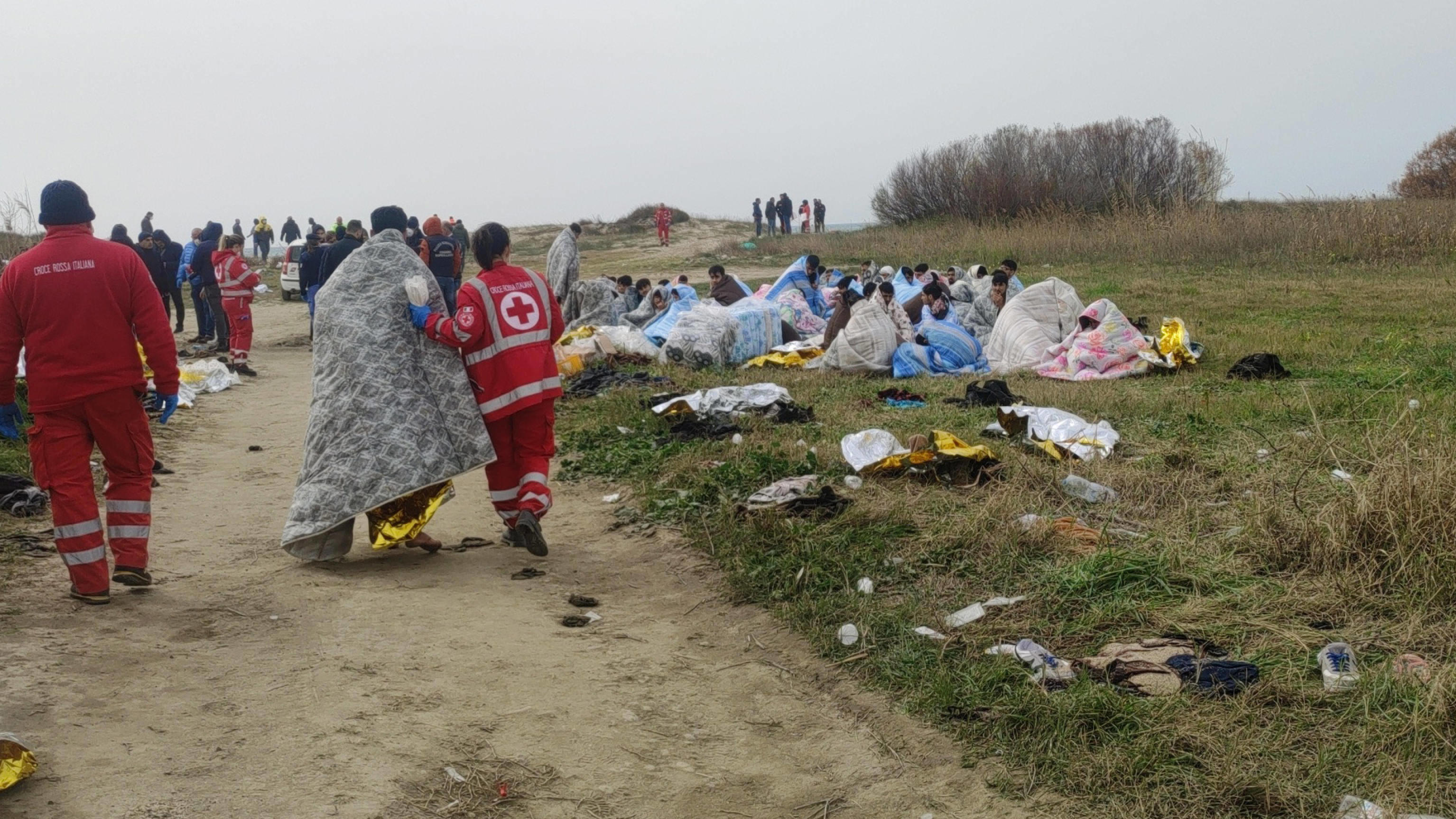 February 26, 2023, CUTRO: Red Cross personnel stand next to survivors after they washed ashore following a shipwreck, at a beach near Cutro, Crotone province, southern Italy, 26 February 2023. Italian authorities recovered at least 40 bodies on the b
