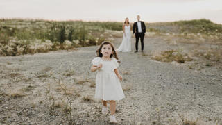 Kleines Kind läuft vor einem Brautpaar