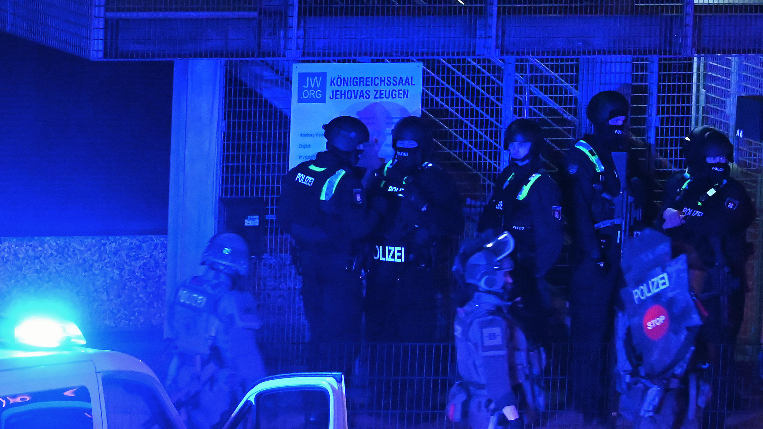 09.03.2023, Hamburg: Polizisten sind in Hamburg im Einsatz und stehen vor einem Schild mit der Aufschrift "Königreichssaal Jehovas Zeugen". Bei Schüssen sind am Donnerstagabend mehrere Menschen getötet und einige Personen verletzt worden.