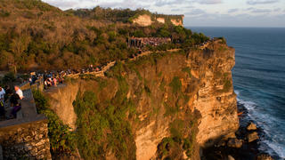 Tourists along the cliffs next to the Ulu Watu temple Pura Luhur. Bali. Uluwatu Temple is a Hindu temple set on the cliff bank in south part of Bali Peninsula. It is one of Sad Kahyangan Temple in Bali (six big groups of Bali Temples), located in Pecatu Village, Sub district of South Kuta, and Badung Regency or about 25 Km southerly part of Denpasar town. It is situated on the coral reef sordid to sea about 80 meters above the sea level. It is featured by a small dry forest which is mostly called by Alas Kekeran (interdict forest) which is belong to the temple and dwelt by a lot of monkeys and other animal. Name of Uluwatu was come from the word Ulu meaning the head and Watu meaning stone. Therefore Uluwatu Temple mean the temple built in tip of coral reef. In the right and left of temple building or Pelinggih Ida Bagus Ratu Jurit located in complex of Uluwatu Temple, there are two stone mangers that look like a boat. When both of it are united, hence it's look similar to sarcophagus, the famous stone from megalithic era culture. There is archaeology omission coming from 16 centuries in firm of arch or winged entrance gate. Winged entrance gate is one of the scarce archaeology omissions. Winged entrance gate that is existing in Uluwatu Temple (a period of its making) can be compared with the same one located in mosque complex in Sendangduwur Village, Lamongan, East Java. The period of its making is relevant with the year Candrasengkala found at this inscription. Candrasengkala founded in the mosque is written by the wording Gunaning Salira Tirta Hayu meaning year 1483 Saka or 1561 Masehi.If the sarcophagus that existing in Dalem Jurit complex area represents the artifact, hence Uluwatu Temple represents the place sanctified since era of megalithic culture (About 500 S.M). In papyrus of Usana Bali mentioned that Mpu Kuturan (The Hindu Priest who spread out the Hinduism in Bali) had built a lot of temple in this island and one of them Uluwatu Temple. | Verwendung ...