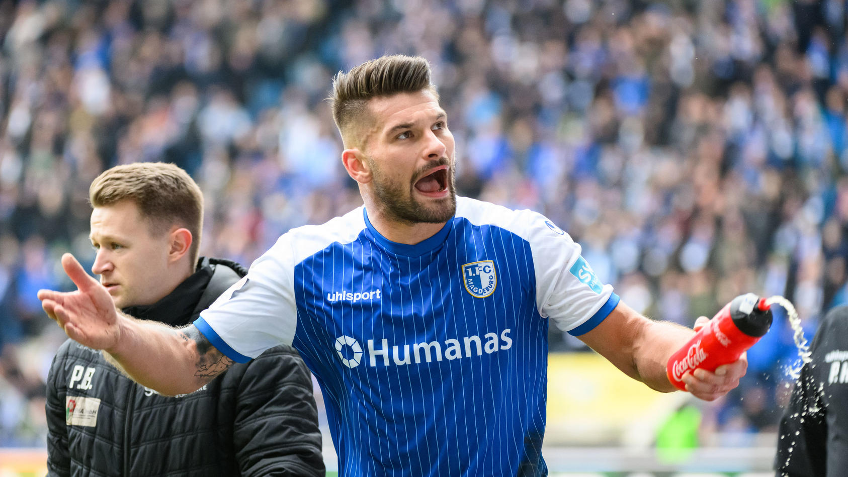 18.02.2023, Sachsen-Anhalt, Magdeburg: Fußball: 2. Bundesliga, 1. FC Magdeburg - FC St. Pauli, 21. Spieltag, MDCC-Arena. Magdeburgs Kai Brünker motiviert die Zuschauer auf der Tribüne. Foto: Christian Modla/dpa - WICHTIGER HINWEIS: Gemäß den Vorgaben