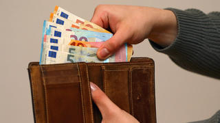 Eine Frau zählt ihre Geldscheine ihrem Portemonnaie.