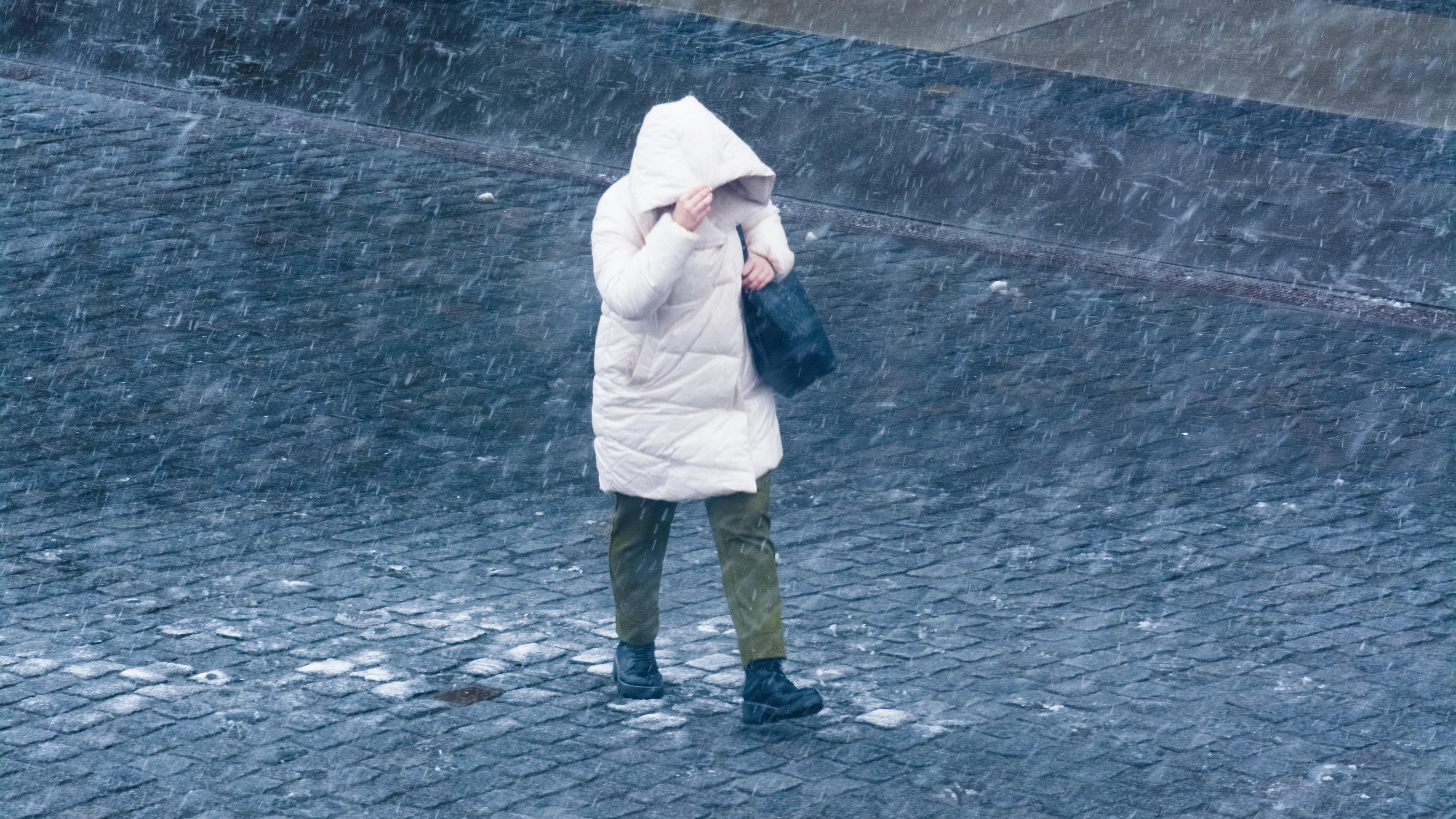 Frau läuft bei Regen durch die Stadt.