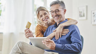 Happy woman embracing man with credit card doing online shopping through tablet PC at home model released, Symbolfoto property released, RORF03132