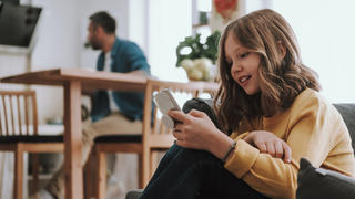Mädchen, das mit ihrem Smartphone auf dem Sofa sitzt.