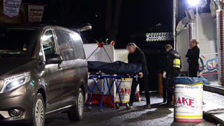19.03.2023, Nordrhein-Westfalen, Münster: Ein Bestatter bringt den Toten mit einer Bahre in sein Fahrzeug. Ein 31 Jahre alter Mann ist nach einer Auseinandersetzung auf dem Send in Münster mit einem Messer niedergestochen worden und gestorben. Ein bislang unbekannter Täter war am Samstagabend auf der Kirmes an einem Karussell mit dem 31-Jährigen in Streit geraten. Foto: David Poggemann/Nord-West-Media /dpa +++ dpa-Bildfunk +++