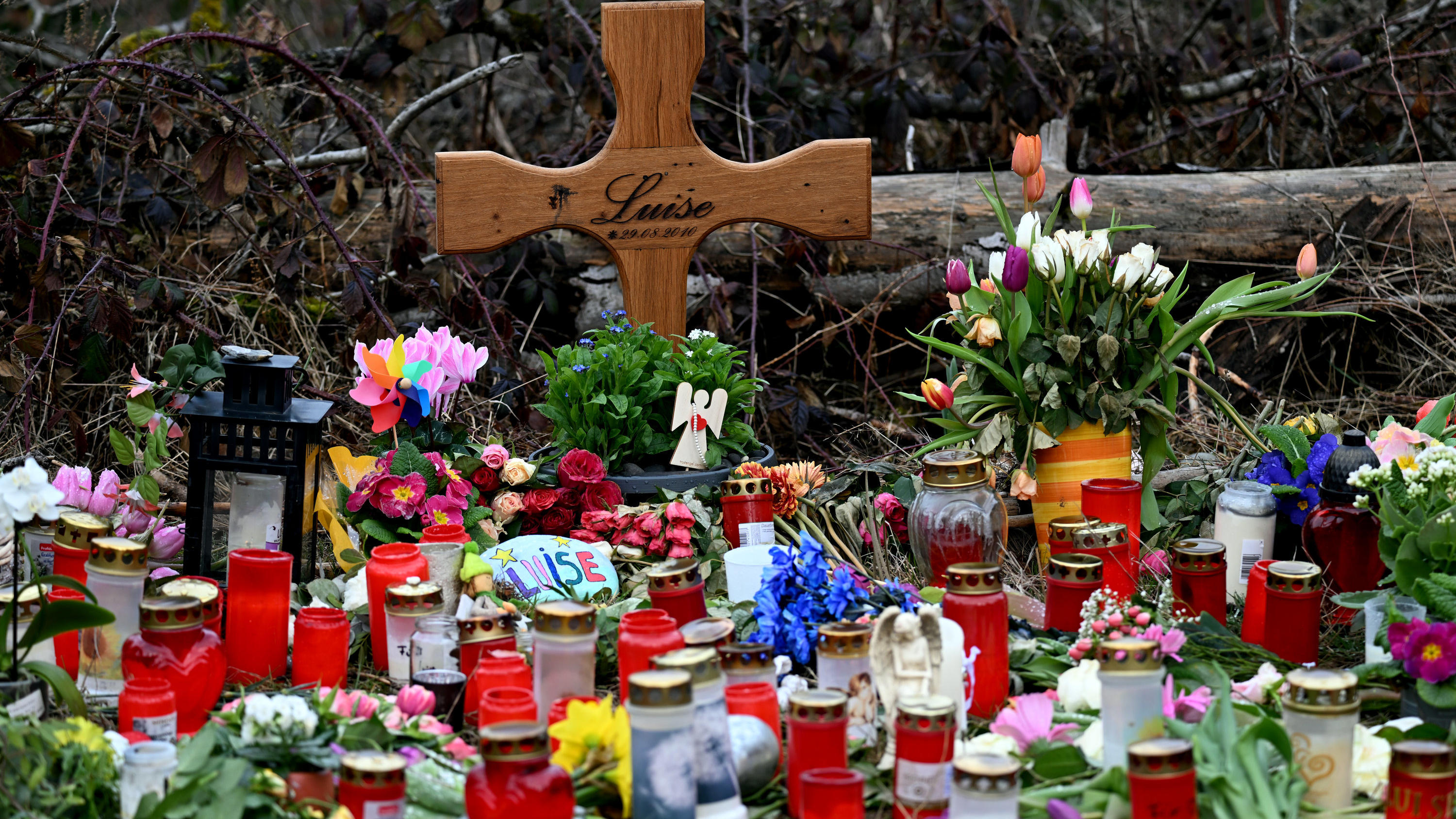 dpatopbilder - 22.03.2023, Nordrhein-Westfalen, Freudenberg: Ein Holzkreuz, zahlreiche Blumen, Kuscheltiere und Kerzen liegen am Tatort. Mit einer Trauerfeier nehmen Angehörige der getöteten zwölfjährigen Luise aus Freudenberg im Siegerland Abschied 