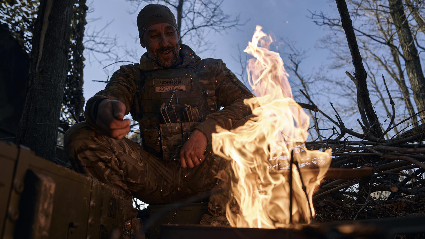 22.03.2023, Ukraine, Bachmut: Ein ukrainischer Soldat ruht sich an der Frontlinie in der Region Donezk an einem Feuer aus. Foto: LIBKOS/AP +++ dpa-Bildfunk +++