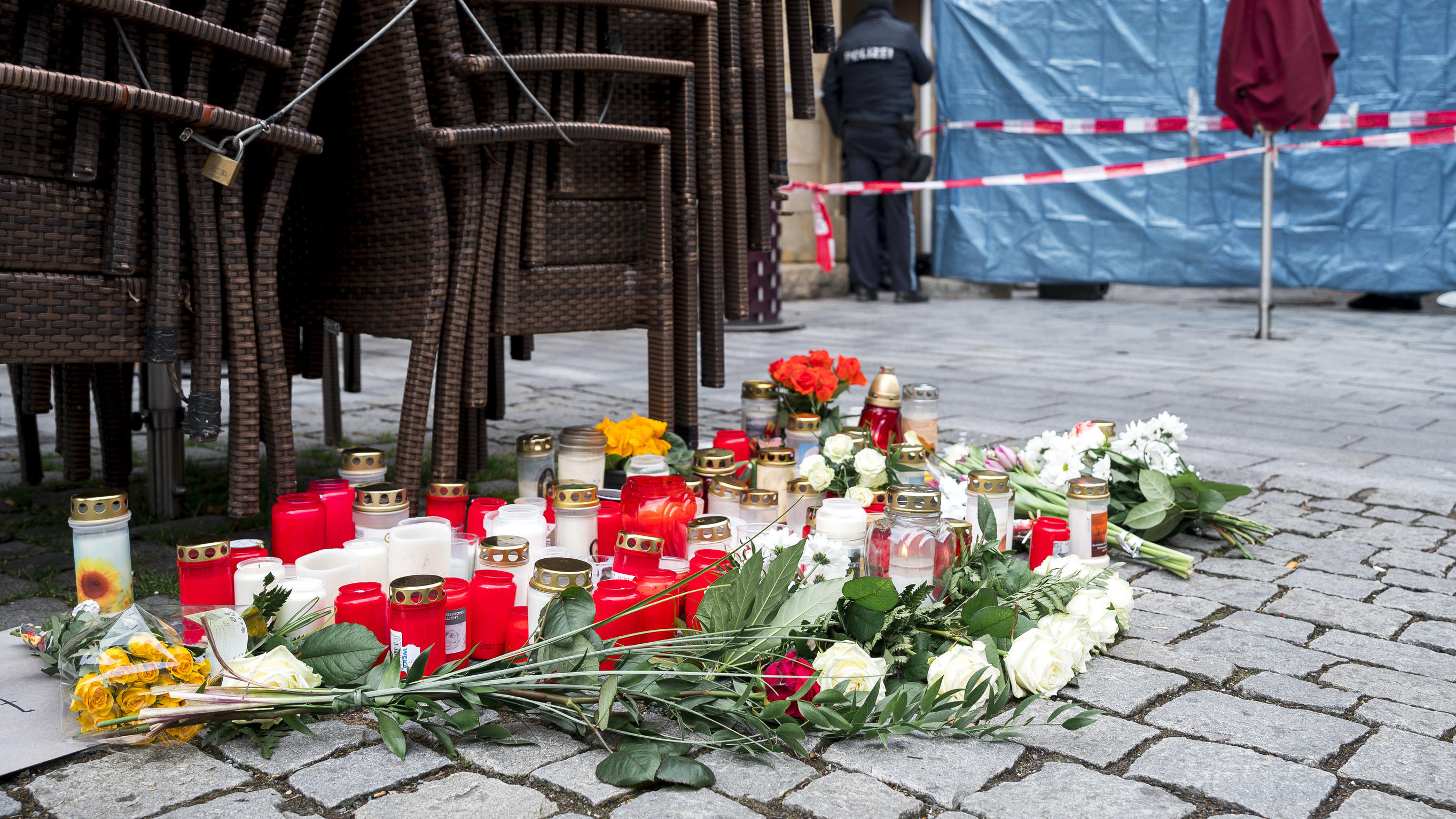 13.03.2023, Bayern, Lichtenfels: Auf dem Platz vor dem Blumengeschäft, in dem am Freitagabend Mitarbeiterin tot aufgefunden wurde, sind Blumen und Kerzen niedergelegt. Spaziergänger hatten die tote 50-Jährige in dem Blumenladen in der Lichtenfelser I