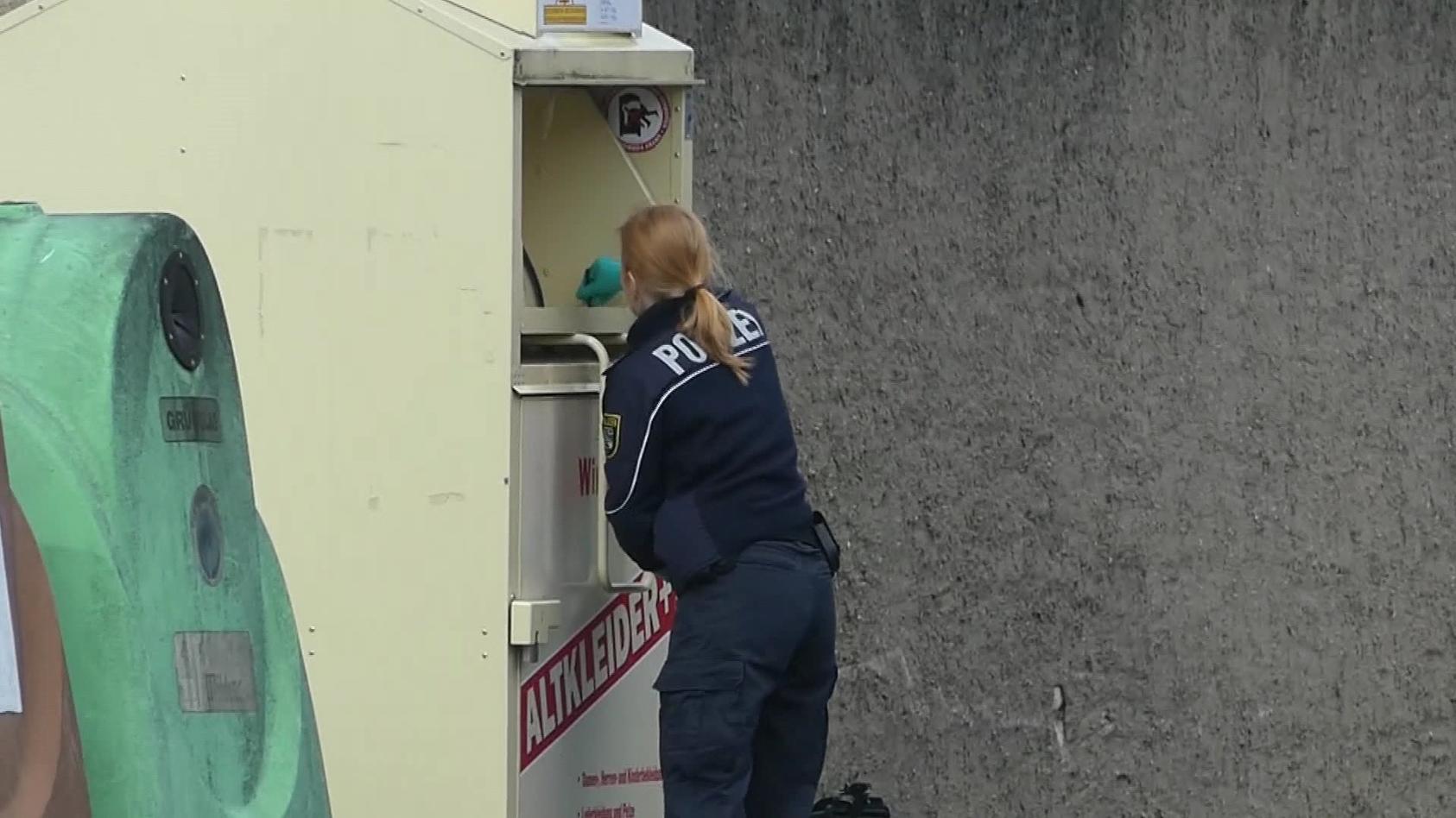 Eine Polizistin nimmt beim Altkleidercontainer Spuren