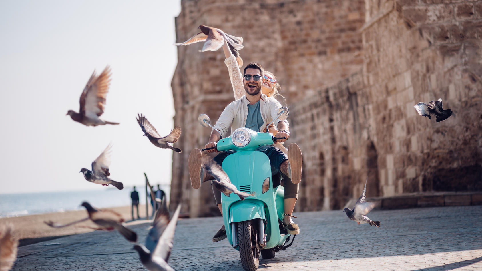 Una coppia in sella a uno scooter attraverso il mare.