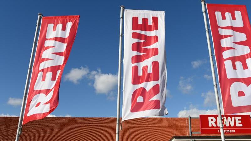 fahnen-mit-dem-logo-des-lebensmitteleinzelhandlers-rewe-wehen-vor-einer-filiale-foto-uwe-zucchidpaarchivbild