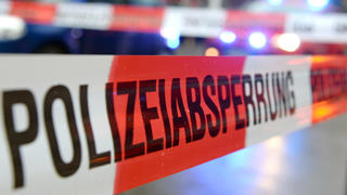 ARCHIV  - Ein Flatterband mit der Aufschrift «Polizeiabsperrung» ist am 05.11.2014 in Freiburg (Baden-Württemberg) an einem Einsatzort vor einem Feuerwehrfahrzeug mit Blaulicht zu sehen (Illustration zum Thema Polizeiabsperrung). Mehrere Menschen sind in München (Bayern) von einem Unbekannten mit einem Messer angegriffen und verletzt worden. Foto: Patrick Seeger/dpa +++(c) dpa - Bildfunk+++
