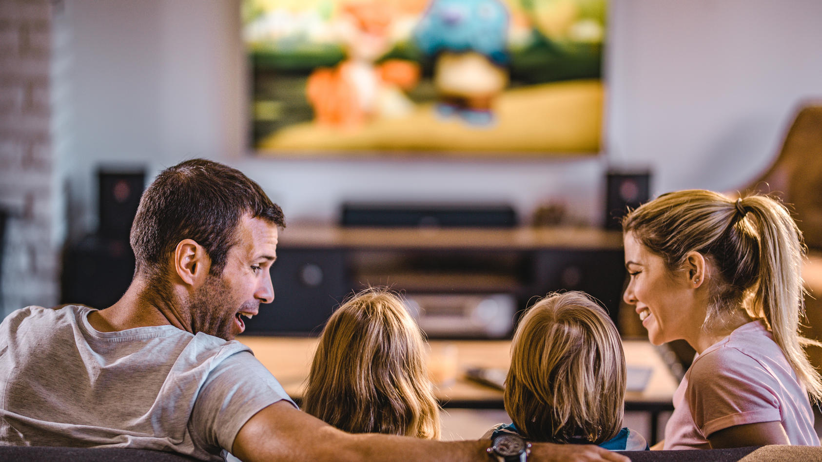 Fröhliche Familie sitzt auf dem Sofa und guckt Fernsehen