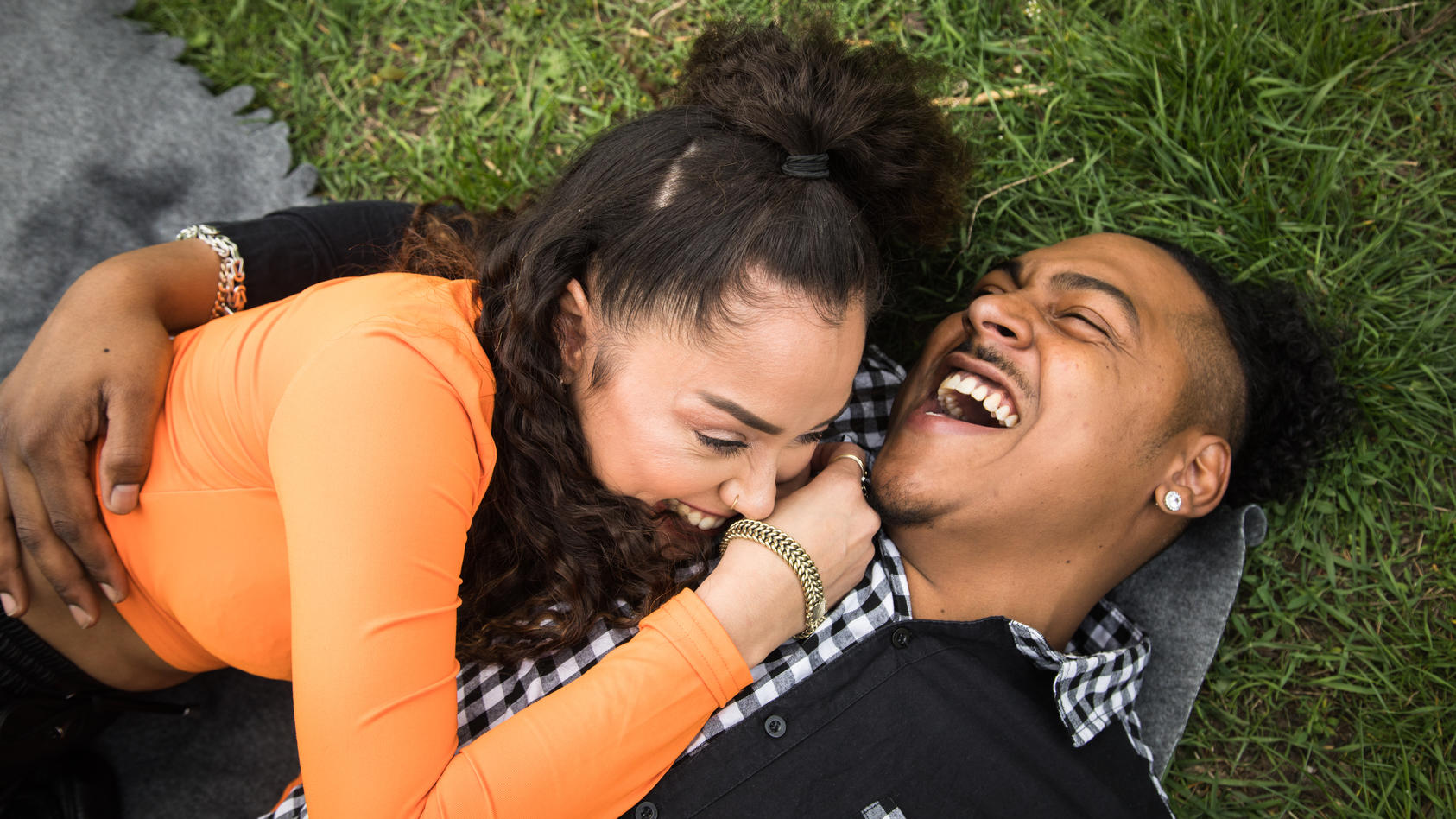 Paar liegt lachend auf einer Wolldecke im Park