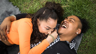 Paar liegt lachend auf einer Wolldecke im Park