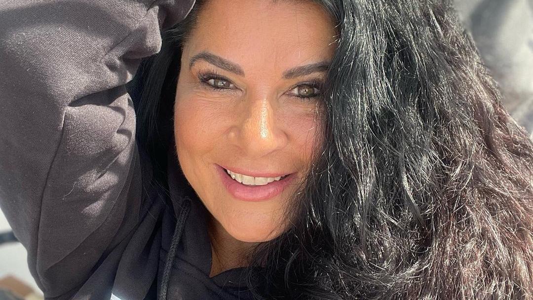 Selfie von Iris Klein, auf dem sie einen Arm über ihren Kopf hält und in die Kamera lacht.