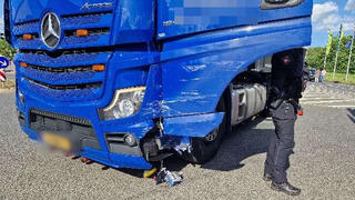 Ein blauer LKW steht auf einer Kreuzung, im Lack sind Kratzspuren zu erkennen.