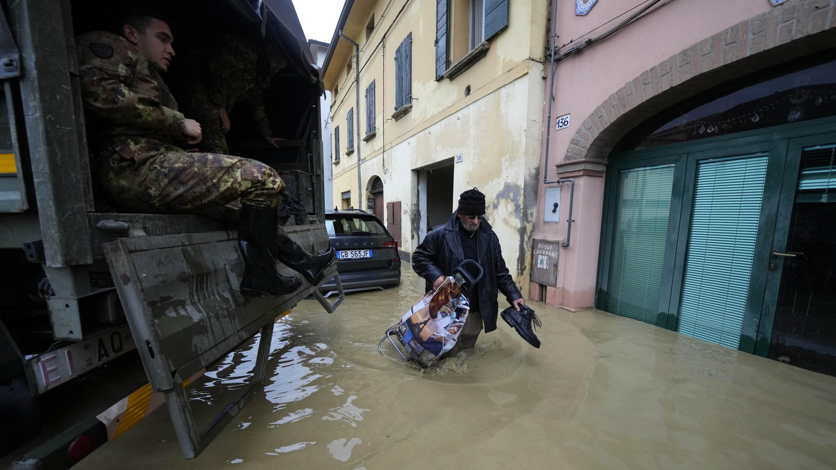 uberschwemmungen-in-teilen-italiens-ein-anwohner-geht-an-einem-armeelastwagen-in-einem-uberschwemmten-dorf-vorbei