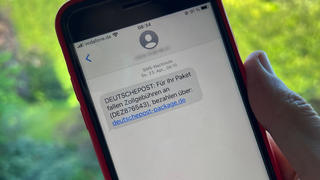 17.05.2023, Nordrhein-Westfalen, Düsseldorf: Ein Mann hält ein Smartphone mit einer betrügerischen SMS. Die Anzahl von betrügerischen SMS, in denen Verbraucher zur Zahlung von angeblichen Zollgebühren aufgefordert werden, hat stark zugenommen. In den SMS wird ein Paket angekündigt, das im Zoll festhänge. Erst wenn Zollgebühren entrichtet werden, werde die Sendung weitergeschickt, heißt es in den Betrugs-SMS, in denen auch ein Link steht. (Zu dpa: "Betrügerische Zollgebühren-SMS nehmen stark zu") Foto: Wolf von Dewitz/dpa - ACHTUNG: Telefonnummer wurde aus rechtlichen Gründen gepixelt +++ dpa-Bildfunk +++