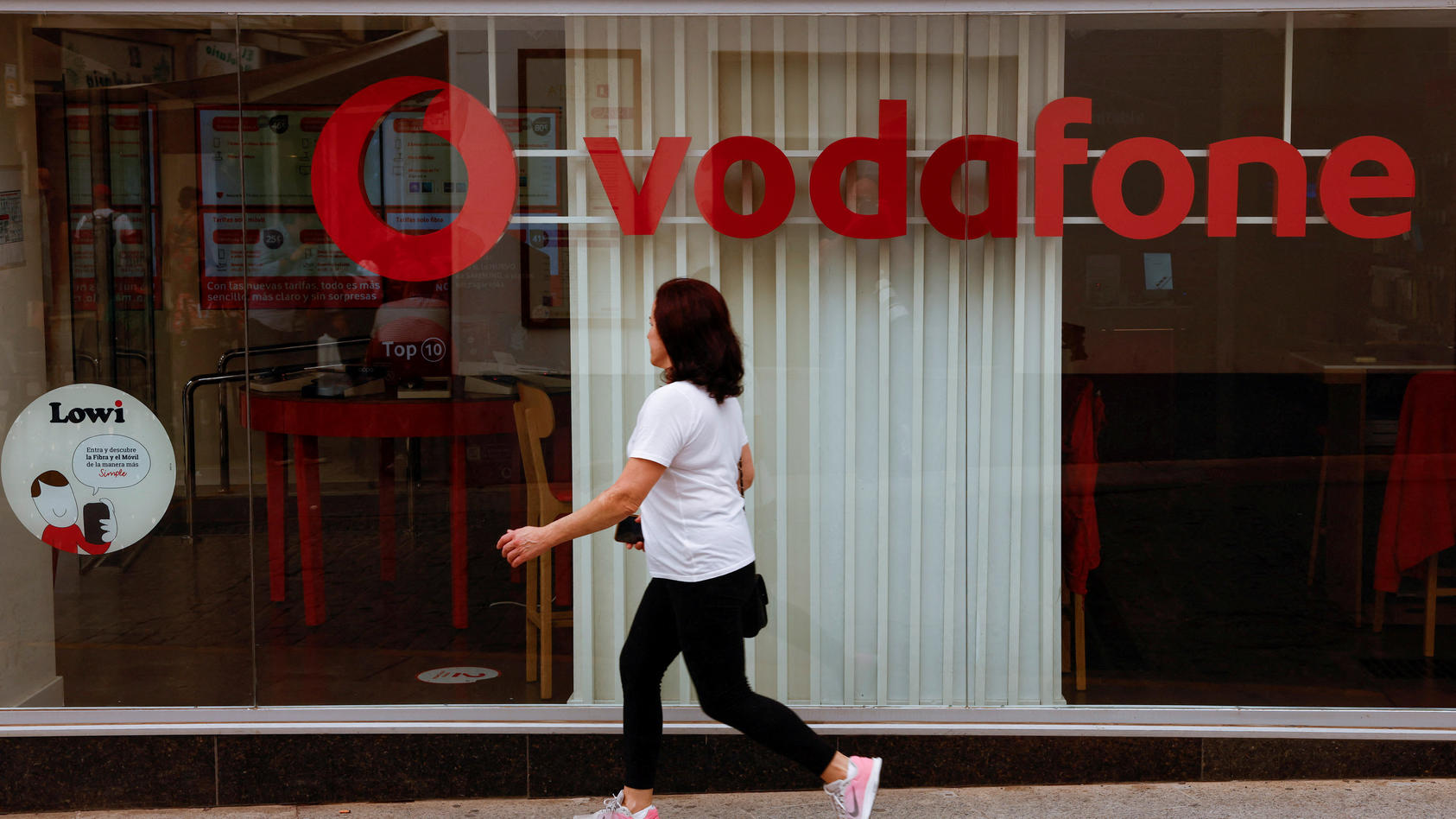 FILE PHOTO: A woman walks past a Vodafone store in Ronda, Spain, October 3, 2022. REUTERS/Jon Nazca/File Photo