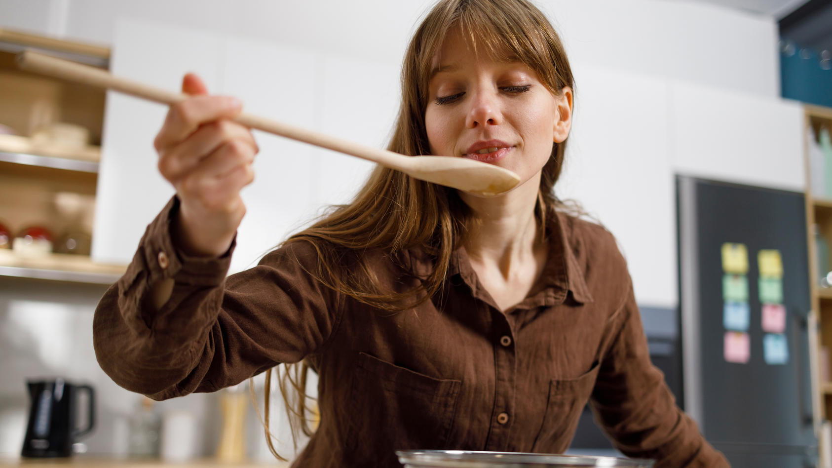 Frau kocht mit Holzkochlöffel.