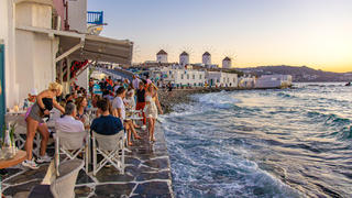 The iconic windmills of Mykonos island as seen from Little Venice with tourists at the bars, cafes and restaurants. Mykonos is an island in Greece in the Aegean sea. There are 16 windmills on the island, 5 of them above Chora, the main town in the island. The windmills were built in the 16th century from the Venetians but their constructions continued until the 20th century. Sunset with people at the windmills in Mykonos. Tourists enjoy a beautiful sunset during the magic hour at Mykonos island in Greece. The Greek island of Myconos is a popular glamorous Mediterranean travel destination for holidays in the Cyclades, Aegean Sea with the iconic whitewashed buildings, the sandy beaches and famous party at the beach bars. The tourism and travel industry had a negative impact in the business and local economy sector due to the Covid-19 Coronavirus pandemic. Mykonos island, Greece(Photo by Nicolas Economou/NurPhoto)