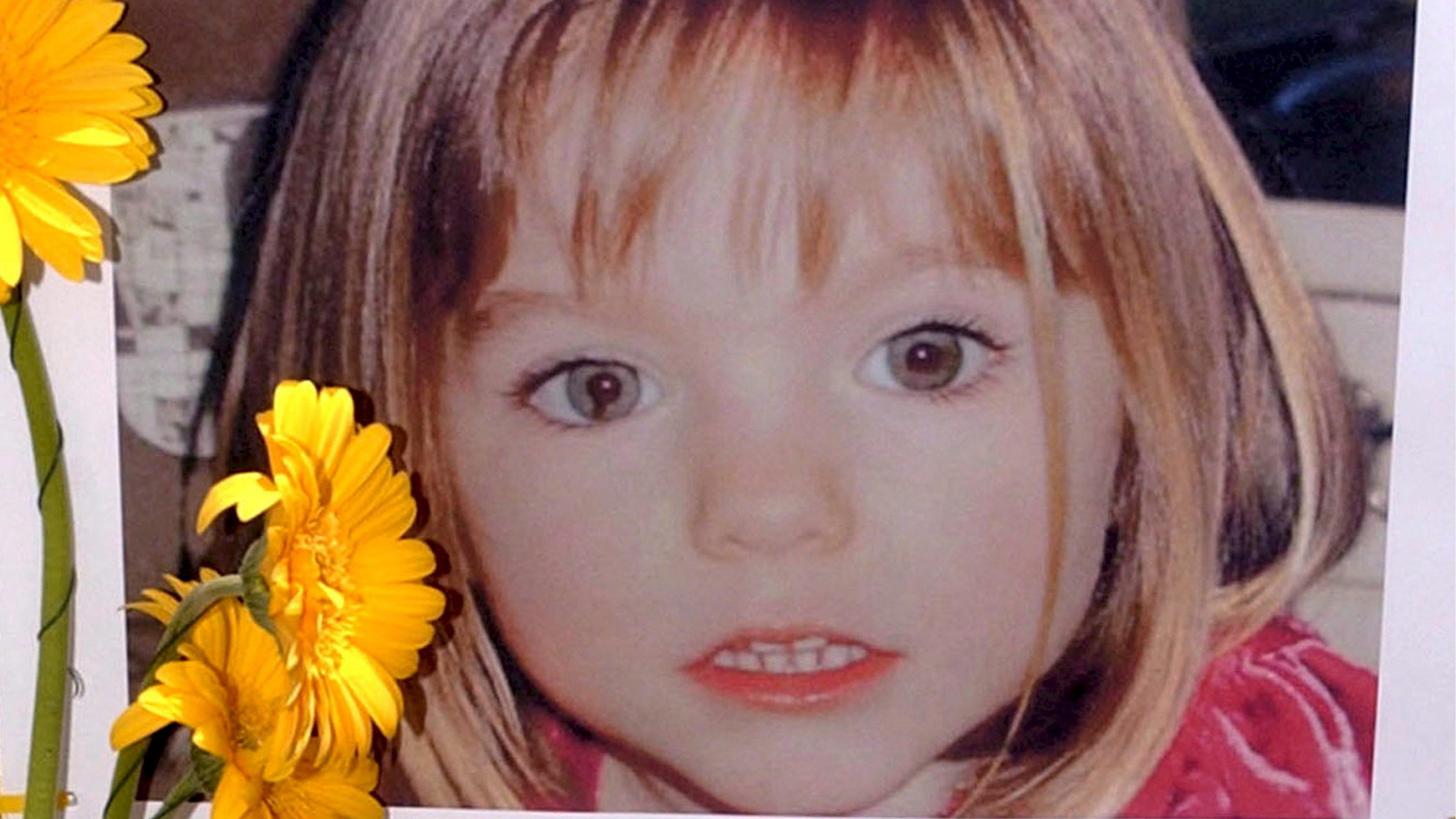 ARCHIV - 12.05.2007, Portugal, Lagos: Blumen stehen vor einem Bild, das die verschwundene Madeleine McCann (Maddie) auf einem Foto zeigt, das ihre Eltern im Zusammenhang mit dem Verschwinden des Kindes veröffentlich haben. Gut 16 Jahre nach dem Versc