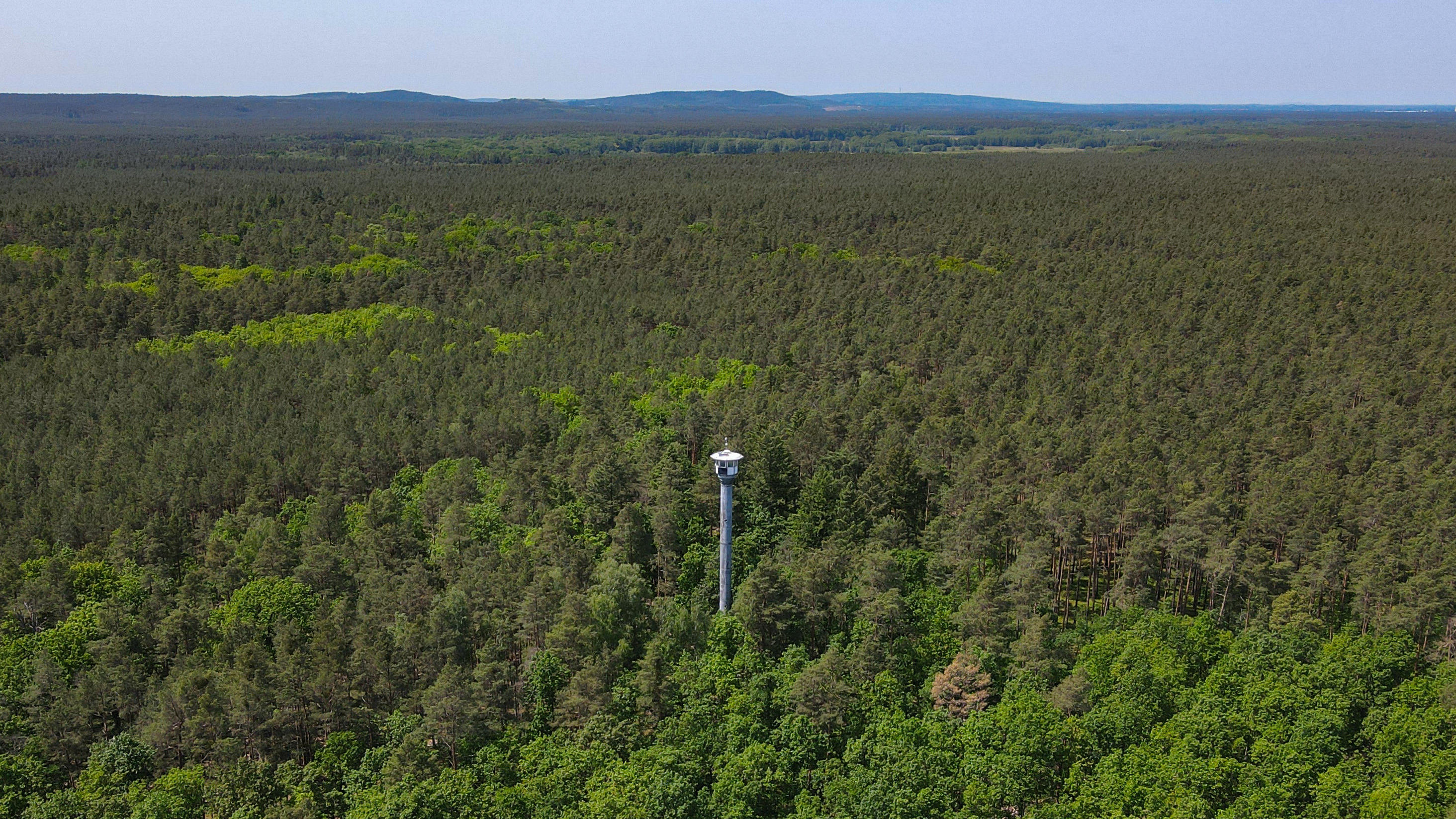 26.05.2023, Brandenburg, Briesen: Ein Feuerwachturm mit Funktechnik und Kamera zur Überwachung von Bränden ist in einem großen Waldgebiet nahe Briesen (Mark) vom Landesbetrieb Forst Brandenburg zu sehen (Luftaufnahme mit einer Drohne). Mit den steige