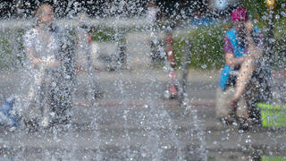 31.05.2023, Bayern, München: Zwei Frauen sitzen in der Innenstadt an einem Springbrunnen in der Sone. Auch in den kommenden Tagen läd das sonnige Wetter zu Erfrischungen in Brunnen ein. Foto: Sven Hoppe/dpa +++ dpa-Bildfunk +++