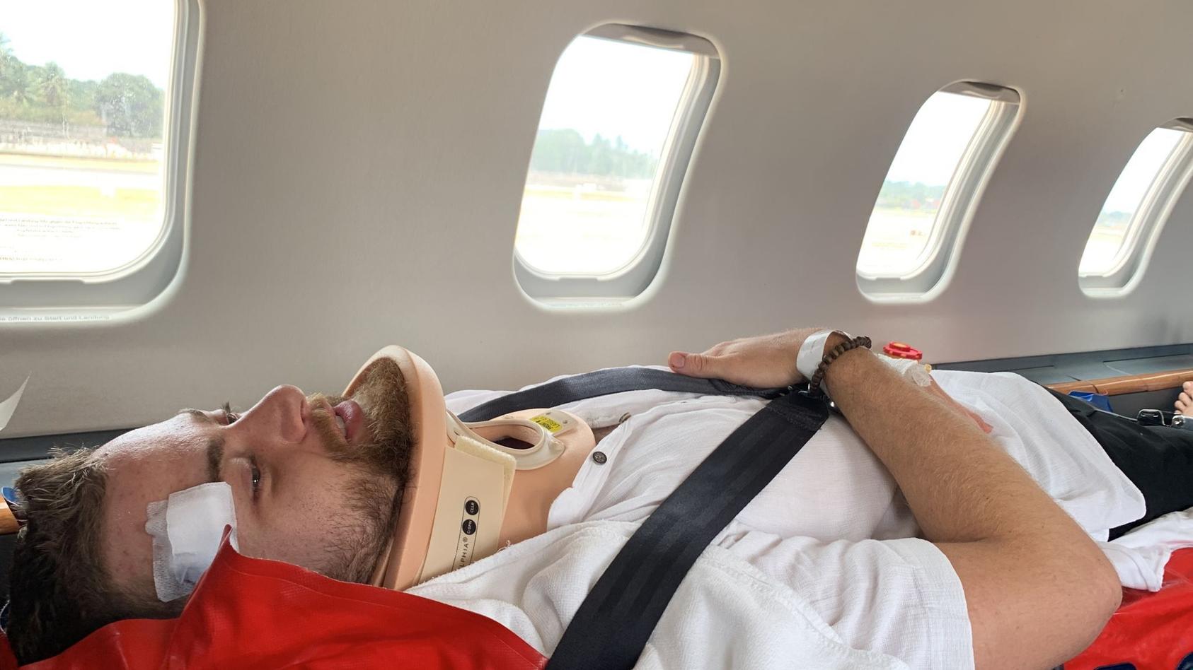 Erik liegt auf der Trage im Krankentransport zurück nach Deutschland.