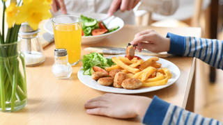 Vegane Nuggets und Pommes auf deinem Teller, daneben Kinderhände