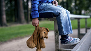 Ein Junge sitzt verlassen auf einer Park.