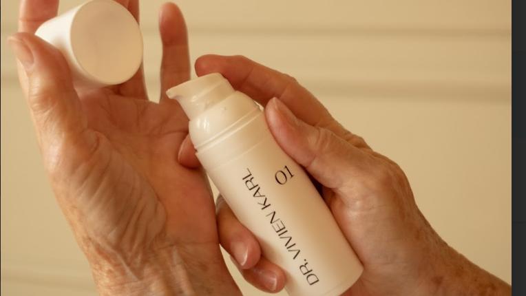 Hände halten Spender mit Creme von Dr. Vivien Karl