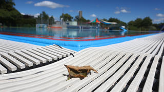 03.08.2023, Bayern, Augsburg: Ein Herbstblatt liegt im Freibad Bärenkeller am Beckenrand des menschenleeren Nichtschwimmerbeckens. Foto: Karl-Josef Hildenbrand/dpa +++ dpa-Bildfunk +++