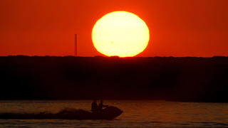 Two men ride a jet ski as the sun sets over the Mediterranean Sea coastline in Beirut, Lebanon, Wednesday, July 12, 2023. (AP Photo/Bilal Hussein)